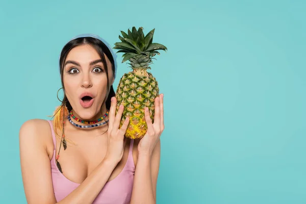 Excited woman in bandana holding pineapple isolated on blue — Stock Photo