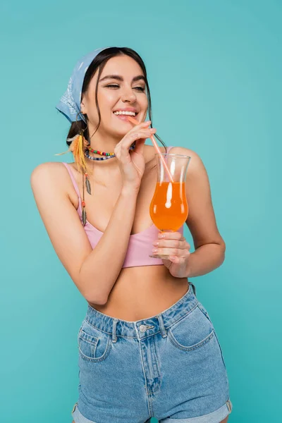 Красивая женщина в верхней и бандана пить коктейль изолирован на синий — стоковое фото