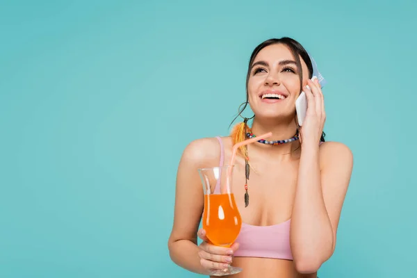 Positive Frau mit Cocktail im Smartphone-Gespräch isoliert auf blau — Stockfoto