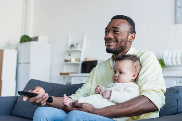 Homme afro-américain joyeux regardant le film de comédie avec petite fille — Photo de stock