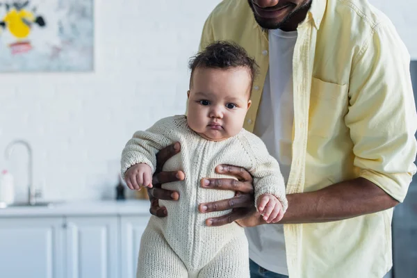 Enfant en bas âge en tricot barboteuse dans les mains du père afro-américain — Photo de stock