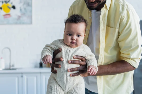 Niño infante en mameluco de punto en manos del padre afroamericano — Stock Photo