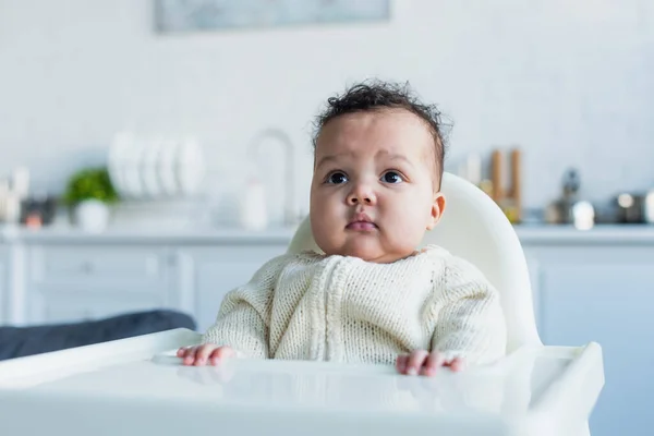 Afrikanisch-amerikanisches Säuglingsmädchen schaut weg, während es im Babystuhl sitzt — Stockfoto