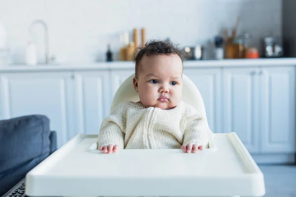 African american infant girl sitting in baby chair in kitchen — Stock Photo