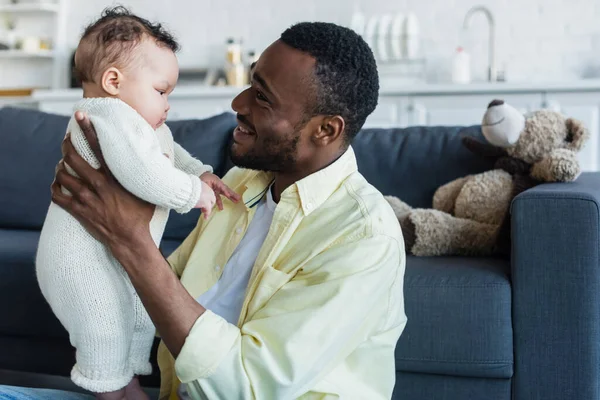 Felice uomo afro-americano che tiene la figlia neonata a casa — Foto stock
