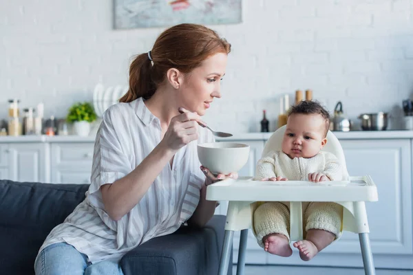 Frau füttert afrikanisch-amerikanische Tochter mit Frühstück in Küche — Stockfoto