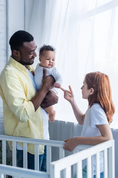Preteen fille touchante main de bébé soeur près souriant afro-américain père — Photo de stock