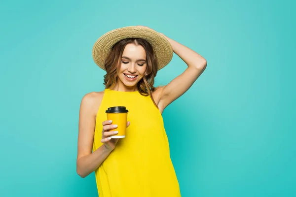 Mulher feliz em chapéu de sol segurando café para ir isolado em azul — Fotografia de Stock