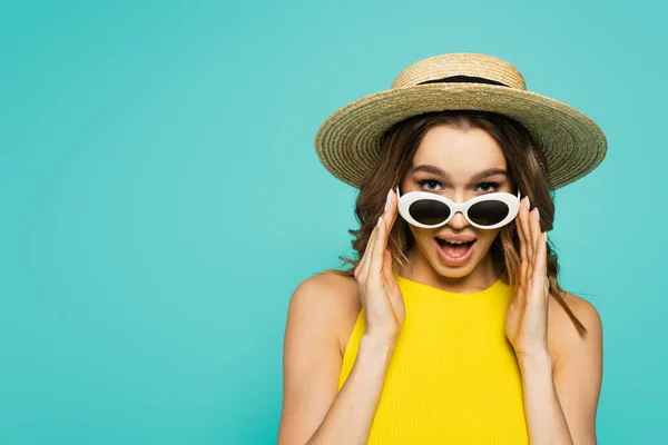 Excited woman in straw hat holding sunglasses isolated on blue — Stock Photo