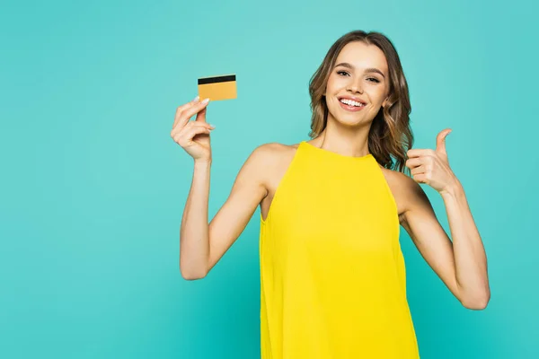 Mujer sonriente con tarjeta de crédito mostrando como aislado en azul - foto de stock
