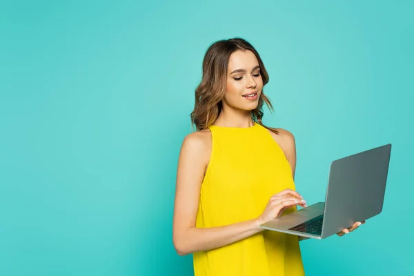 Mujer bonita usando el ordenador portátil aislado en azul - foto de stock