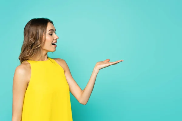 Erstaunte Frau zeigt mit Hand isoliert auf blau — Stockfoto