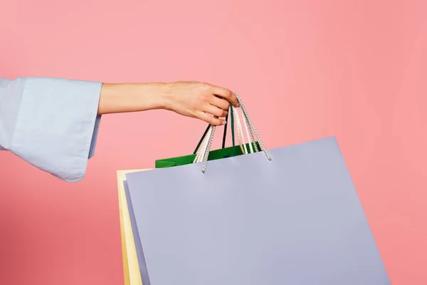 Vista cortada de mulher segurando sacos de compras isolados em rosa — Fotografia de Stock