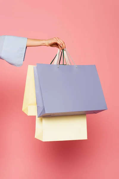 Vista cortada da mão feminina segurando sacos de compras isolados em rosa — Fotografia de Stock