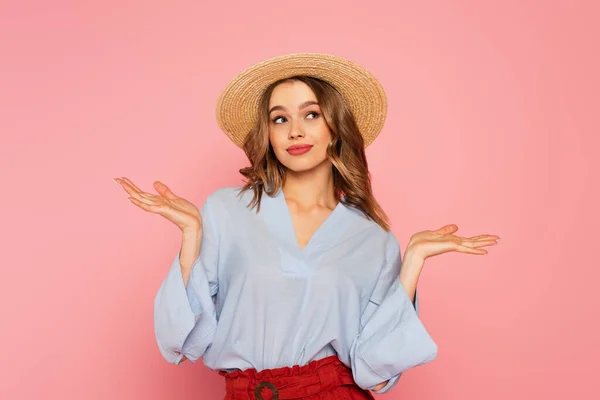 Mujer con estilo en sombrero de paja señalando con las manos aisladas en rosa - foto de stock