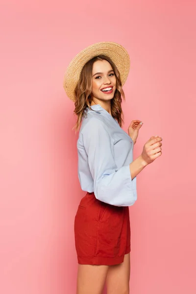 Stylish woman in straw hat dancing on pink background — Stock Photo