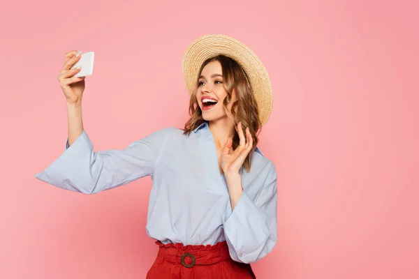 Fröhliche Frau mit Strohhut bei Videoanruf auf Smartphone isoliert auf rosa — Stockfoto