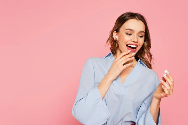 Mulher excitada segurando fone de ouvido isolado em rosa — Stock Photo