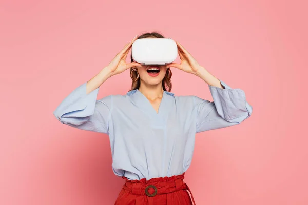 Удивительная женщина, играющая в гарнитуру виртуальной реальности на розовом фоне — стоковое фото