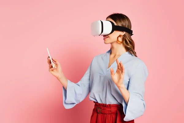 Stylish woman in vr headset using smartphone on pink background — Stock Photo