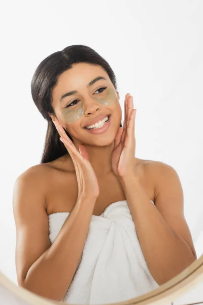 Young african american woman holding hands near face with eye patches in bathroom — Stock Photo