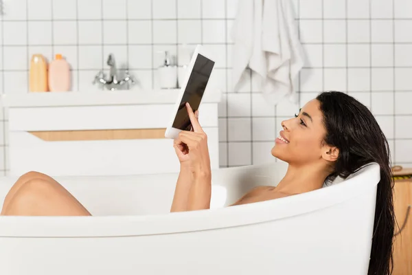 Junge afrikanisch-amerikanische Frau badet und nutzt digitales Tablet mit leerem Bildschirm — Stockfoto