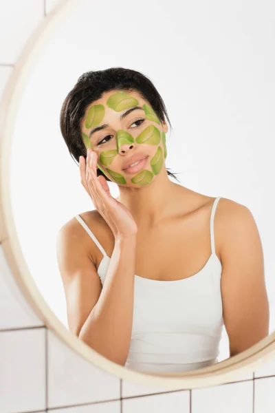 Young woman touching face with green mask near window in bathroom — Stock Photo
