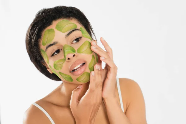 Fokussierte junge Frau trägt grüne Maske auf Gesicht mit Händen auf weißem Hintergrund auf — Stockfoto