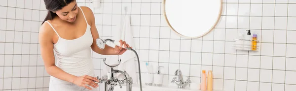 Giovane donna afroamericana in abiti bianchi che tiene in mano il soffione della doccia, striscione — Foto stock