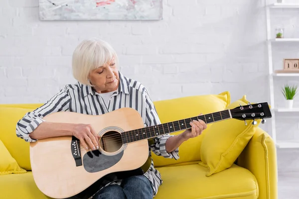 Mujer mayor tocando la guitarra acústica en casa - foto de stock