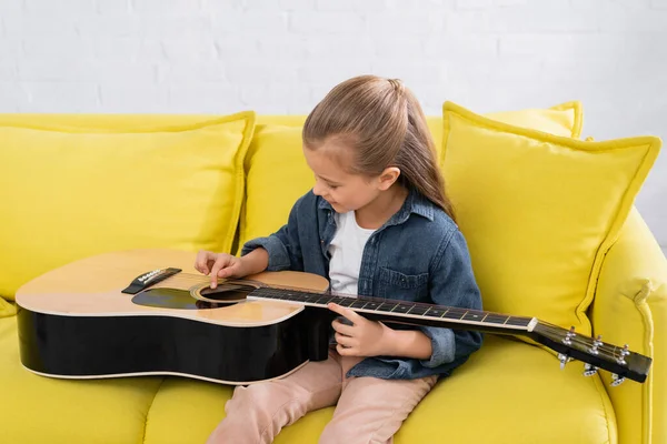 Chica tocando la guitarra acústica en el salón - foto de stock