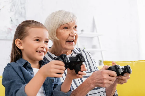 KYIV, UKRAINE - JANUARY 11, 2021: Smiling granny playing video game with child — Stock Photo