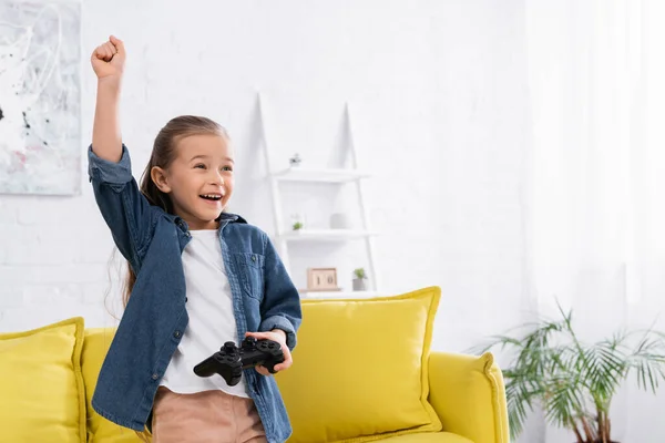 KYIV, UKRAINE - JANUARY 11, 2021: Excited girl with joystick showing yes gesture at home — Stock Photo