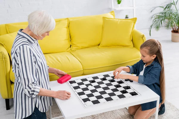 Niño y abuelo jugando damas juego a bordo - foto de stock