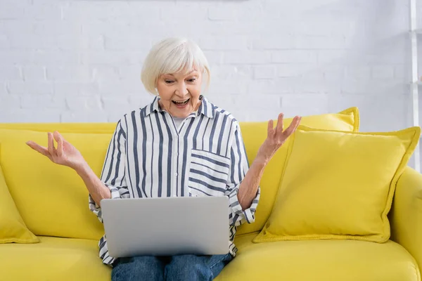 Mujer sorprendida usando el ordenador portátil en la sala de estar - foto de stock