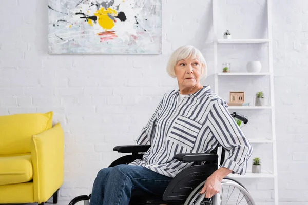 Elderly woman sitting in wheelchair in living room — Stock Photo