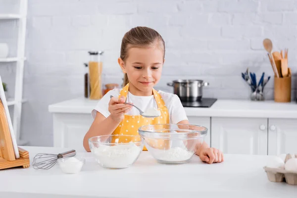 Fröhliches Kind gießt Mehl neben digitalem Tablet und verschwommenen Eiern — Stockfoto