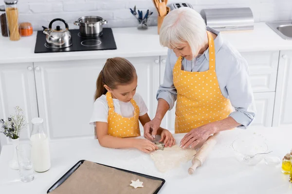 Visão de ângulo alto de menina e avó preparando biscoito perto da assadeira — Fotografia de Stock