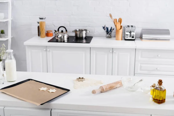 Massa, cortador de biscoitos e rolo de pino na mesa perto da farinha na cozinha — Fotografia de Stock