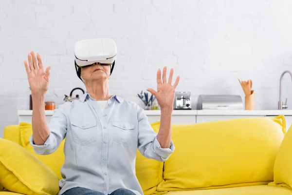 Mujer mayor jugando videojuego en auriculares vr en casa - foto de stock