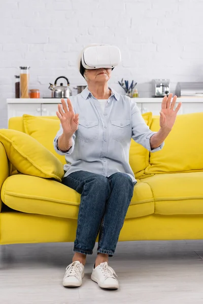 Senior woman in vr headset sitting on couch — Stock Photo