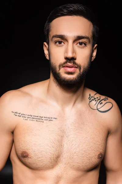 Shirtless tattooed man looking at camera isolated on black — Stock Photo