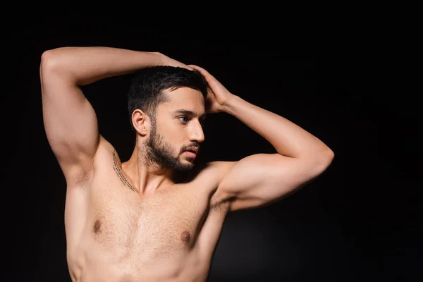 Musclé homme posant et regardant loin isolé sur noir — Photo de stock