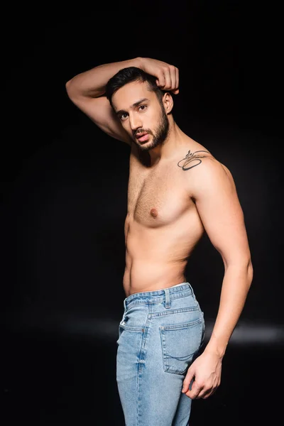 Shirtless man in jeans posing on black background — Stock Photo