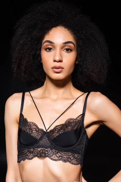 Afro americano donna in pizzo reggiseno guardando fotocamera isolato su nero — Foto stock