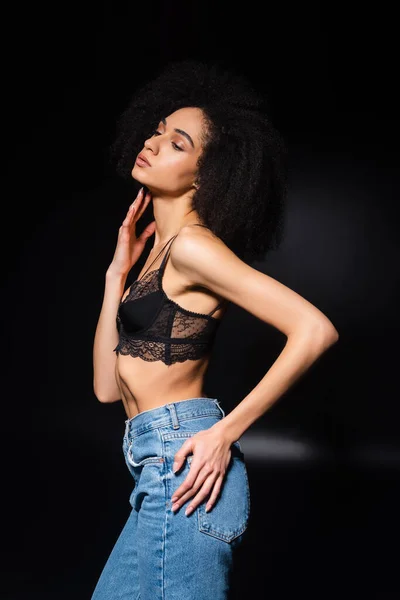 Femme afro-américaine en soutien-gorge en dentelle regardant loin sur fond noir — Photo de stock