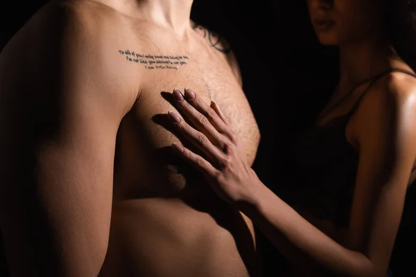 Cropped view of african american woman touching torso of tattooed boyfriend isolated on black — Stock Photo