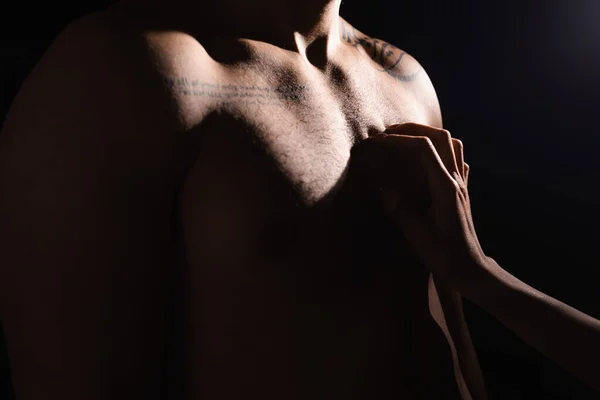 Ausgeschnittene Ansicht einer Frau, die Brust eines tätowierten Mannes kratzt, isoliert auf schwarz — Stockfoto