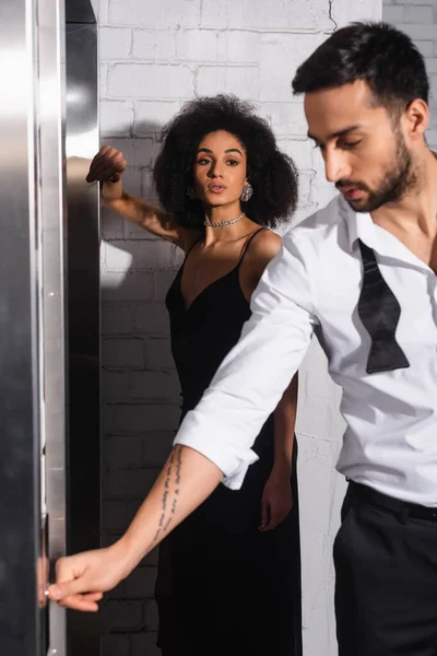 Mujer afroamericana mirando a su novio en primer plano borroso cerca del ascensor - foto de stock