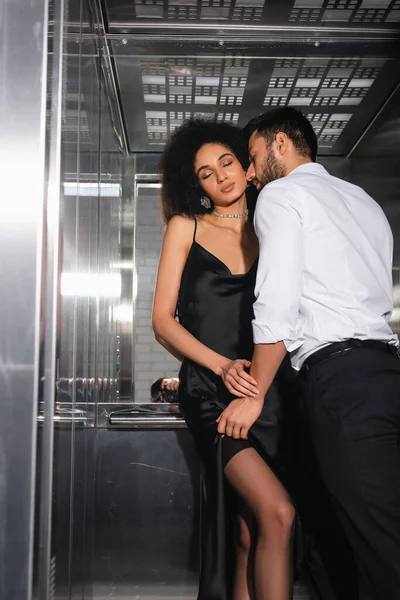 Barbudo hombre besos sexy africano americano mujer en ascensor - foto de stock